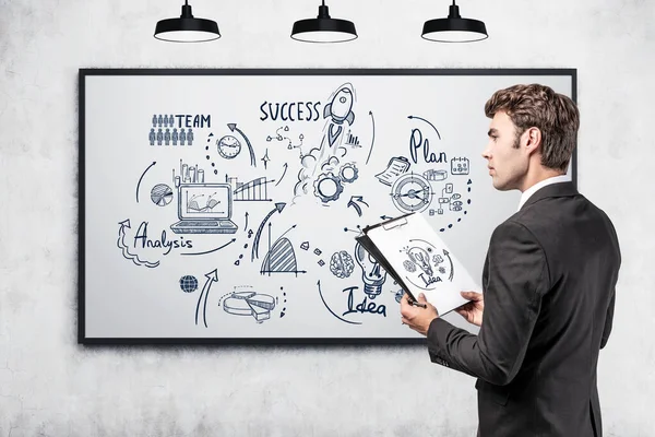 Office man in suit with business files in hands, business strategy plan in a frame on grey wall. Doodle drawing with arrows, graphs and network icons. Concept of analysis
