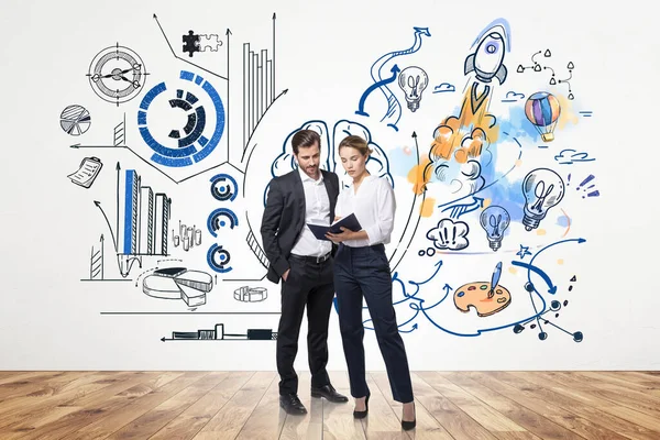 Businesswoman and businessman standing on parquet floor, studying business notes. Colourful drawing with different icons of thinking process on white wall. Concept of business ideas and plans