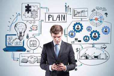 Siyah takım elbiseli bir ofis çalışanı akıllı telefonuyla yazı yazıyor, iş stratejisi planı, finansal analiz ve çalışma süreciyle çizim yapıyor. Teknoloji kavramı ve başlangıç