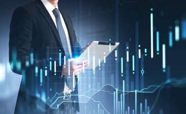 Resmi takım elbiseli bir işadamı, elinde tablet ve borsa raporuyla hologram kullanıyor. Ticarette iş ve finansal başarı kavramı. Çifte maruziyet. Temel analiz.