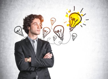 Siyah takım elbiseli bir ofis çalışanı, arka plan karalaması gri beton arka plan üzerine çizilmiş çoklu ampul, bir de parlak sarı lamba. En iyi fikir ve çözüm kavramı