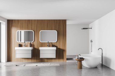 Banyo içi beton zeminde küvet, iki ayrı lavabo ve aynalar. Mobilyalı, duşlu, minimalist, beyaz ve gri bir oda.