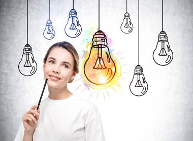 Çenesine kalem yemiş düşünceli bir kadın, zeki bir öğrenci. Gri arka planda çizilmiş ampul karalaması, renkli bir lamba. Yeni fikir ve eğitim kavramı