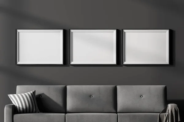 客厅内部有三幅空白的白色海报挂在墙上 灰色沙发紧贴着 舒适会合点的概念 把它弄坏了3D渲染 — 图库照片