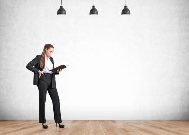 Siyah takım elbiseli ofis kadını iş raporlarını okuyor, parke katta. Yönetici lambalarla birlikte iş notlarını inceliyor. Boş duvarı kopyala. İş analisti kavramı.