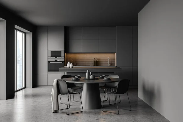 Interior of stylish kitchen with gray walls, concrete floor, comfortable round dining table with four chairs, bar and cupboards. Blurry cityscape window. 3d rendering