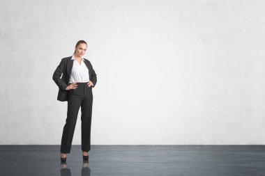 Beton zeminde siyah takım elbiseli bir ofis kadını. Ofis odasında kendine güveni olan bir yönetici. Kopya alanı boş duvar, iş adamı konsepti ve plan.