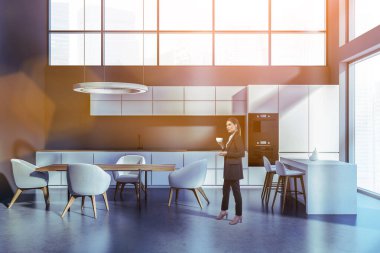 Mutfak odasında uzun, çekici bir kadın. Mobilyaları var, resmi kıyafetler giyiyor, kahve içiyor, lens parlıyor. Lüks yemek odasında ya da şirket kantininde çalışan iş kadını imajı.