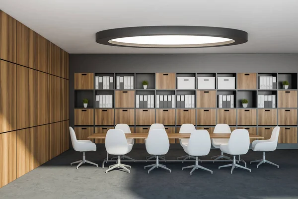 Interior of futuristic and classic hotel business center meeting room with gray and wooden walls, long conference table with white chairs and bookcase with binders and folders. Round lamp 3d rendering
