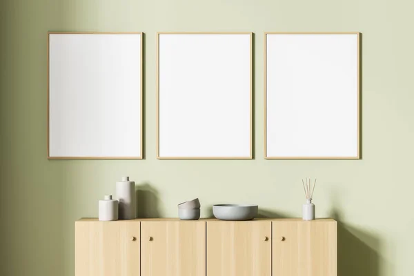 Art room interior with wooden drawer and vase with ceramic plates, minimalist decoration in relaxing room. Three blank posters in a row, mock up on wall, 3D rendering