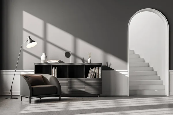 Interior of classic living room with gray and white walls, concrete floor, comfortable gray armchair, bookcase and arched door with stairs. 3d rendering