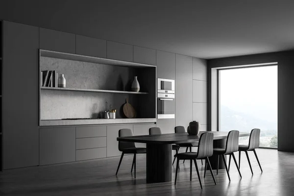 Black kitchen room with long table and six wooden chairs, side view, concrete floor. Cooking set interior with window on countryside, oven and kitchenware, 3D rendering