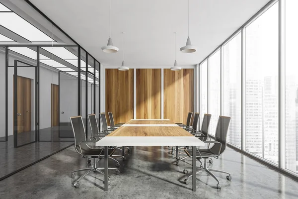 Light conference room interior with row of black armchairs and wooden table, grey concrete floor. Office minimalist furniture in business office with view on skyscrapers, 3D rendering