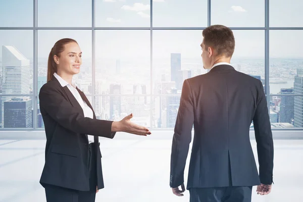 Business people shake hands, woman outstretched hand to man, partner near windows with New York city view. Concept of international connection and teamwork