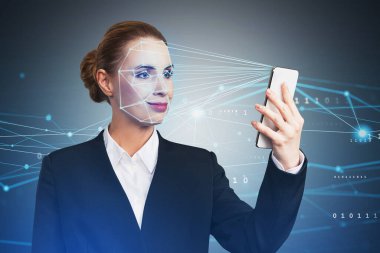 Businesswoman wearing formal suit is checking her personal data. Scanning her face by smart phone to unlock it. Digital connections. Concept of data protection.