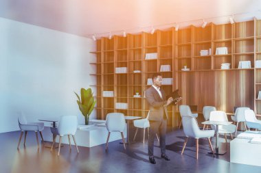 Takım elbiseli düşünceli Asyalı işadamı planlamacıdan not alıyor ve şirket kariyerini hayal ediyor. Şirket kantini, iş bürosu ve ortak çalışma alanları. Modern ortak alan.