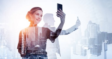 Uzaktan akıllı telefonlar kullanarak iletişim kuran iki meşgul iş adamının siluetleri, çift pozlama. New York gökdelenlerinin arka planı