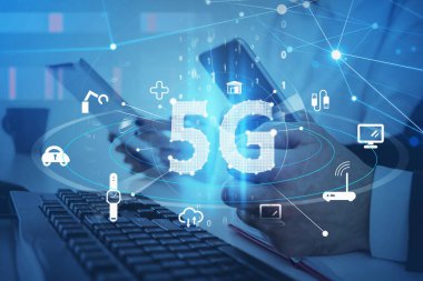 Akıllı telefon da dahil olmak üzere dijital cihazlarla çalışan iki meslektaşı olan bir ofis. 5G dijital ağın mavi hologram simgeleri. Kablosuz sistemler ve yüksek hız sinyali