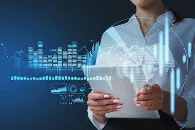 Finansal bar grafiklerinin hologramı dünya ekonomisinin büyüdüğünü gösteriyor, dünya ikonu. İş kadını araştırmaya devam etmek için tablet aygıtı kullanıyor.