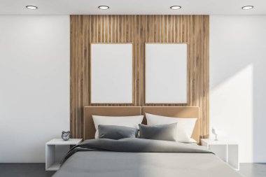 İçinde yatak, büfe, beyaz duvarlar ve gri çarşaflı yatak başlığı, ahşap detaylar, yan masalar var. İki tane poster. 3d oluşturma