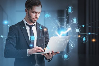 Resmi takım elbiseli yakışıklı sakallı iş adamı dizüstü bilgisayar tutuyor. Kripto para biriminin finansal piyasadaki değerini analiz etme kavramı. Şifreleme para birimi simgeleriyle dijital arayüzün hologramı