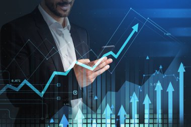 Takım elbiseli iş adamı elinde akıllı telefonla borsa değişikliklerini, çift pozlamayı hologram oklarını ve bar çizelgelerini analiz ediyor. Mali veri kavramı