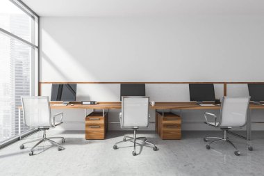 Masalar, monitörler ve yuvarlanan sandalyeler panoramik ofisin beyaz duvarında minimalist iç ve beton gri zeminli sıra halinde duruyorlar. 3d oluşturma