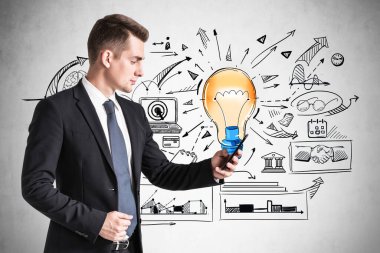 Takım elbiseli iş adamı akıllı telefonuyla interneti tarıyor, başlangıç için yeni fikirler buluyor. Renkli ampul çizimi ve iş akışı şeması. Yaratıcılık ve beyin fırtınası kavramı