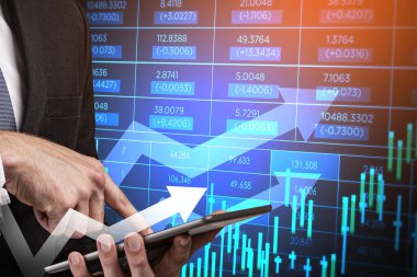 Resmi takım elbiseli bir iş adamı akıllı telefonu elinde tutuyor ve parmağıyla ona dokunuyor. Arka planda eski tablo, grafik ve şamdanlar var. Başarılı ticaret kavramı