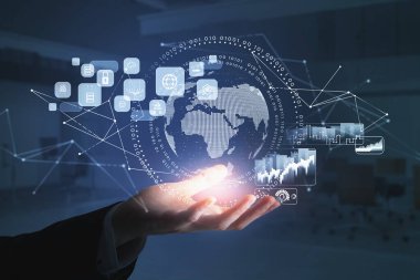 Resmi takım elbiseli iş adamı elinde dünya, bulut verileri, asma kilit ve madeni para simgeleriyle dijital arayüz tutuyor. Arka planda bulanık bir ofis. Uluslararası iş ve iletişim kavramı