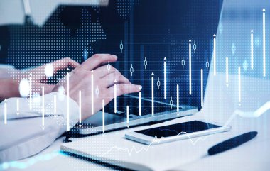 Beyaz gömlek giyen finans simsarı iş yerinde oturuyor ve dizüstü bilgisayarına mesaj yazıyor. Arka plandaki masanın üzerinde akıllı telefon ve defter var. Başarılı ticaret için işbirliği kavramı