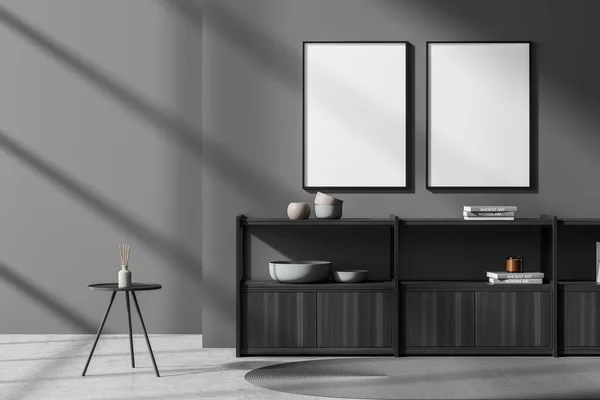 Dark gallery room interior with two white empty poster on the wall, books, sideboard, crockery, coffee table and concrete floor. Concept of minimalist design. Mock up. 3d rendering