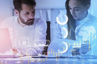 İş adamı ve iş kadını dizüstü bilgisayarda birlikte çalışır ve panoya bakarlar. Ofis arka planda. Ön planda küre, asma kilit, bar ve turta diyagramlarıyla dijital arayüz. Takım çalışması kavramı