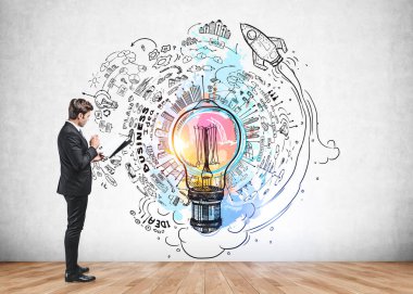 Resmi takım elbiseli iş adamı elinde ampul, roket fırlatma, iş, plan, takım çalışması, beton duvardaki yapboz, ahşap zeminle renkli çizimin yanında duruyor. Yaratıcı fikirler için hayal gücü kavramı