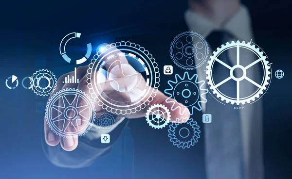 Resmi kıyafet giyen iş adamı, çarklar, dişliler, asma kilit, dünya, insan, bar ve pasta diyagramlarıyla dijital holograma dokunuyor. Arka planda ofis işyeri var. Teknoloji kavramı