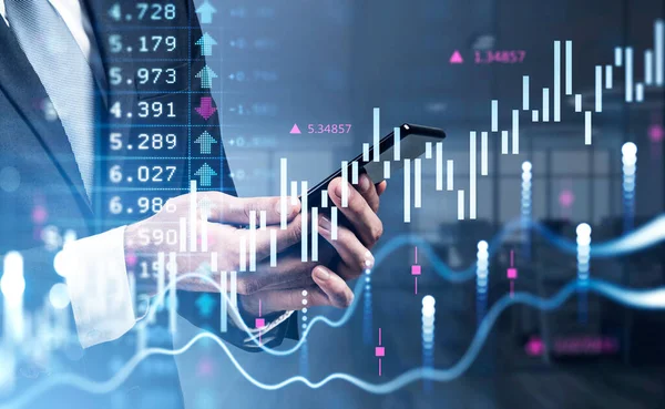 Resmi takım elbiseli bir iş adamı parmağıyla akıllı telefona dokunuyor. Arka planda bulanık ofis işyeri var. Finansal tablo ve grafik ön planda. Ticaret kavramı