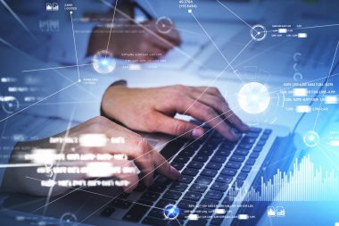 Beyaz tişört giyen iki işadamı dizüstü bilgisayarda birlikte çalışıyor. Arka planda masa olan ofis işyeri. Önplanda daire hologramı, çubuk ve turta diyagramı ile dijital arayüz