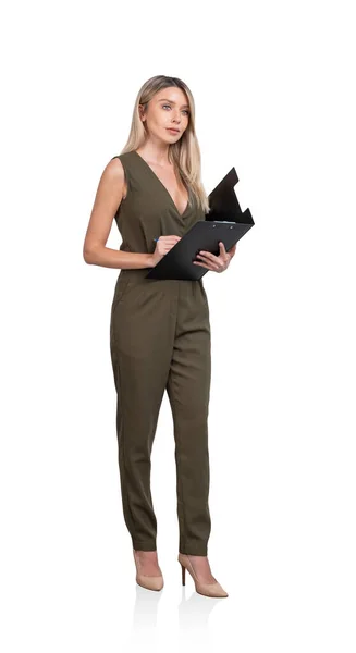 身穿绿色连衣裙的年轻漂亮的女商人站在那里 拿着剪贴板 做笔记 当代成功商人的概念 在白色背景下被隔离 — 图库照片