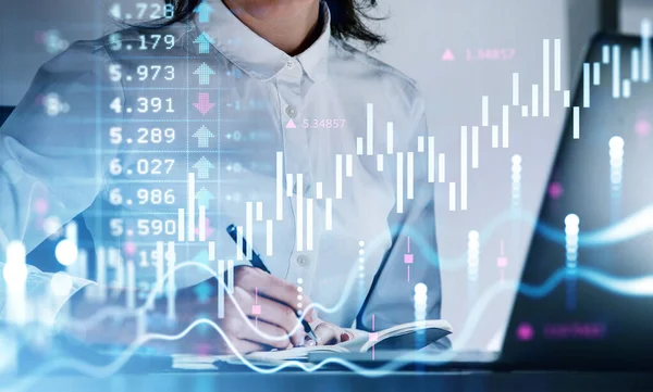 白いシャツを着たビジネスマンがノートにメモを取っている 前景の財務チャートとグラフ 背景にノートパソコン付きのオフィスワークスペース 成功取引の概念 — ストック写真
