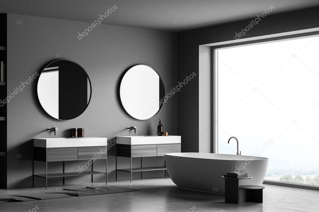 Corner of the dark grey panoramic bathroom interior with the on trend round mirrors over the two vanities, an oval ceramic bathtub and a concrete floor. A concept of modern house design. 3d rendering