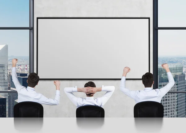 Tres hombre de negocios mirando cartel — Foto de Stock