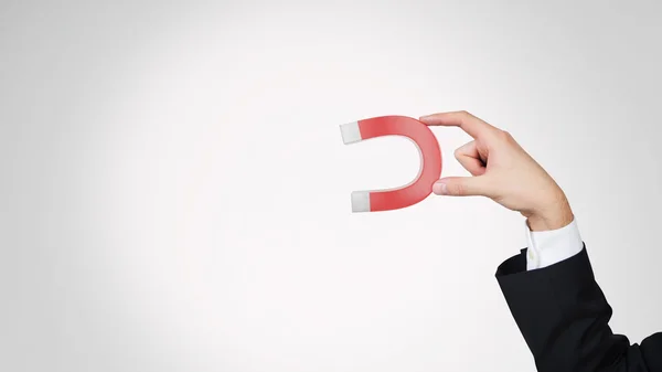 Hand holding red magnet — Stock Photo, Image