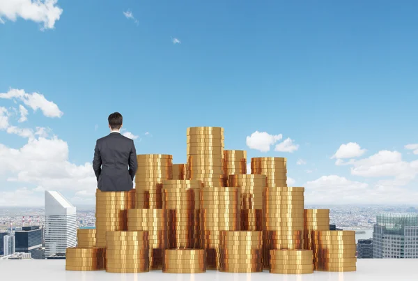 Businessman sitting on coins — Stock Photo, Image