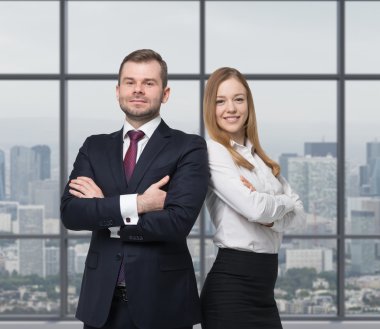 A young business couple are standing in a modern office. New York cityscape. clipart