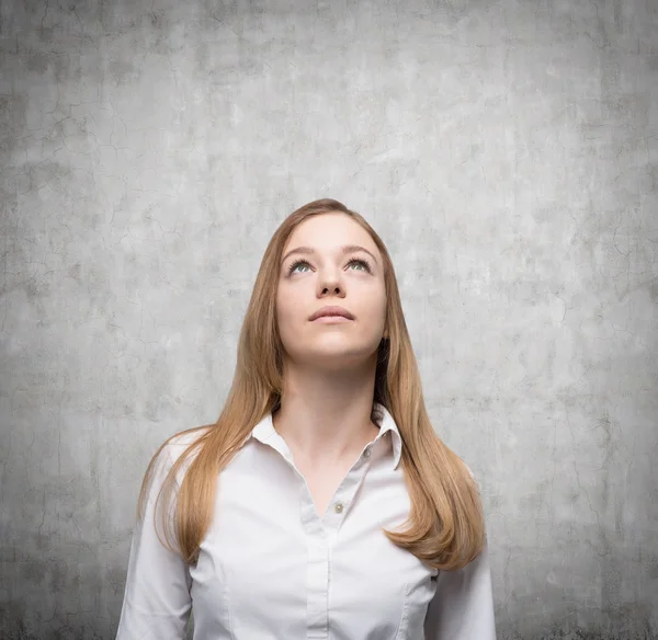 Dreaming young lady is looking up. Concrete background — Stock Photo, Image