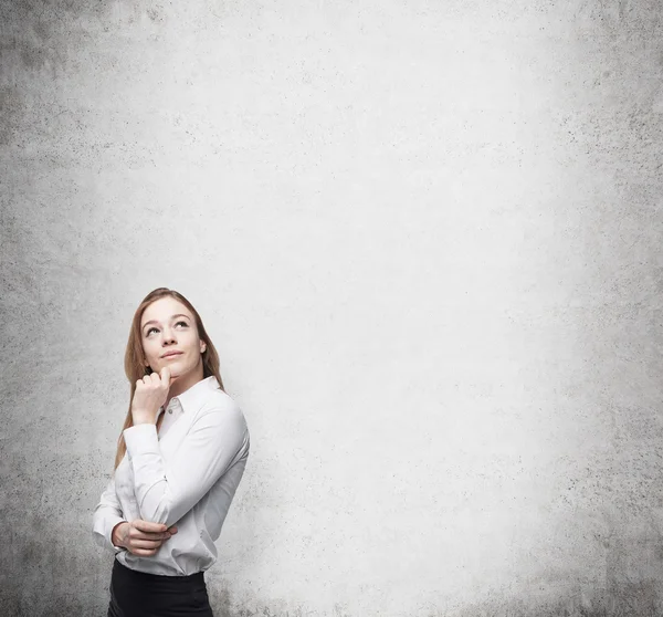 Jonge bedrijf dame is het denken over iets. Concrete achtergrond. — Stockfoto