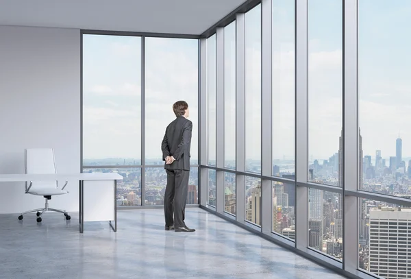 El joven empresario está mirando por la ventana de la esquina. Fondo de Nueva York . — Foto de Stock