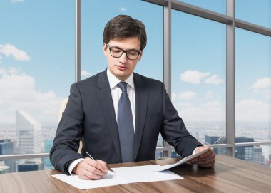 Handsome legal consultant is dealing with due diligence process in a modern skyscraper office with a panoramic New York view. clipart