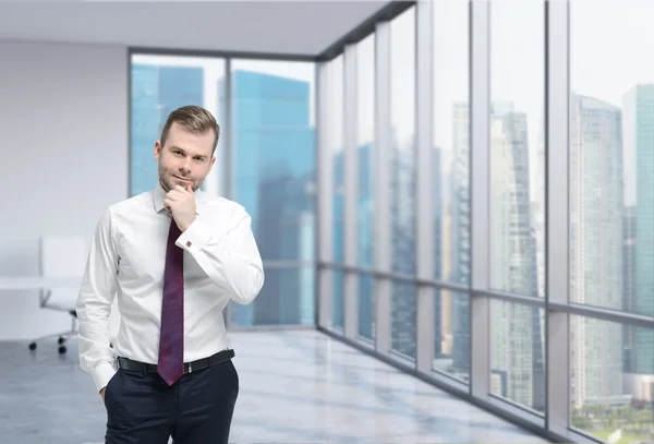 Thinking handsome businessman is standing in a contemporary glass office in New York. — Stock Photo, Image