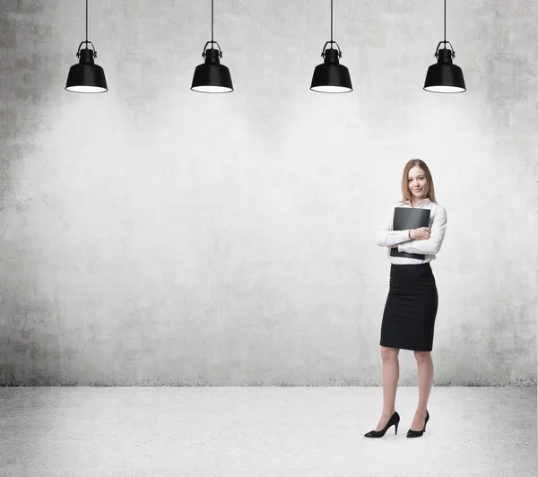 Joven mujer de negocios hermosa está sosteniendo un caso de documento negro. Mujer de negocios está de pie en la sala de oficinas de hormigón . — Foto de Stock